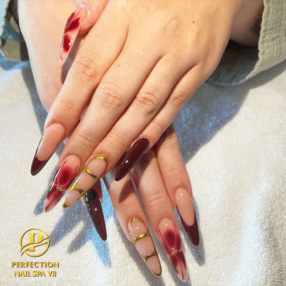 Deep red stiletto nails with gold foil detail